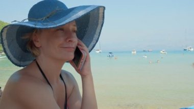 Genç kadın sahilde smartphone üzerinde konuşuyor. Güzel güneşli yaz günü. Yeryüzündeki cennet. Lovrecina beach Island Brac, Hırvatistan.