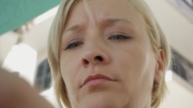 Akıllı telefon kullanan genç üzgün ve sıkıntılı kadın. Kafede şemsiyesi altında oturuyor. Güneşli yaz günü Imotski, Hırvatistan.