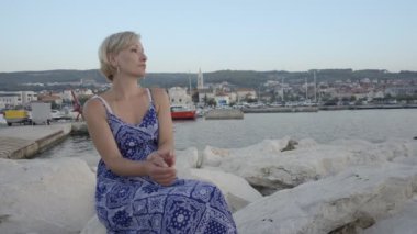 Deniz ve izlerken günbatımı kayaya oturan güzel ve genç birbayan. Yaz tatili Supetar, Island Brac, Hırvatistan, Avrupa.