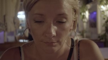 Restoranın terasında oturup ve onun smartphone kullanarak genç kadın. Yaz tatili, gece atış akşam.