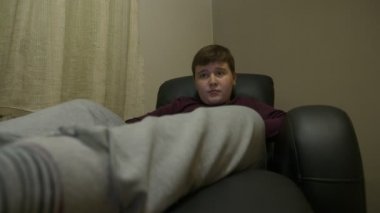 Oturma ve koltukta, rahatlatıcı ve Tv seyretmek genç çocuk. 