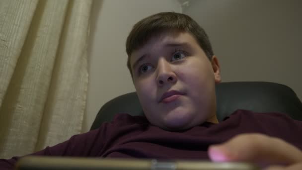 Mladý Chlapec Sedí Relaxaci Křesle Sleduje Televizi Držení Smartphone Svých — Stock video