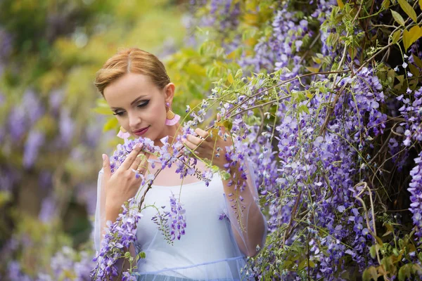 Wisteria, gözleri kapalı zevk çiçek açan, kokulu beyaz genç bir kadın sarışın saçlı mor wisteria yakınındaki portresi