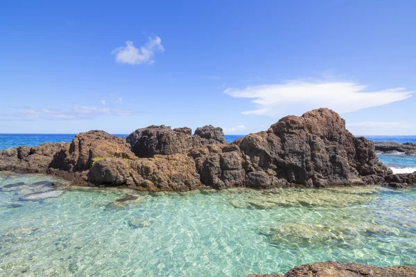 Turquoise pool on rocky tropical sea shore — Stock fotografie