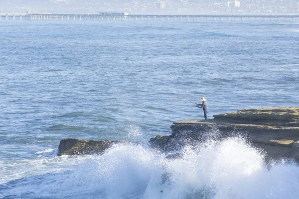 Ondas batendo em torno de surf pescador na costa rochosa em Ocean Bea — Fotografia de Stock