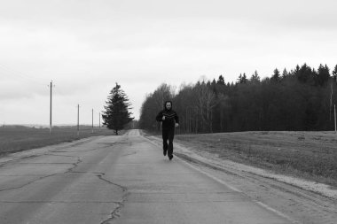 Bir sporcu kırsalında bir karayolu üzerinde çalışıyor