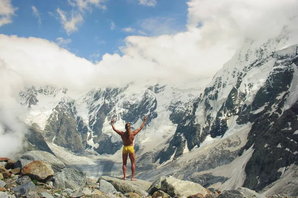山の前にかなりの高さに立っているアスレチック男 — ストック写真