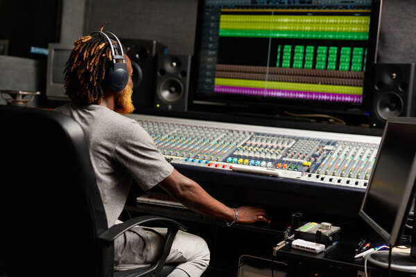 Sound producer sitting by mixing equipment