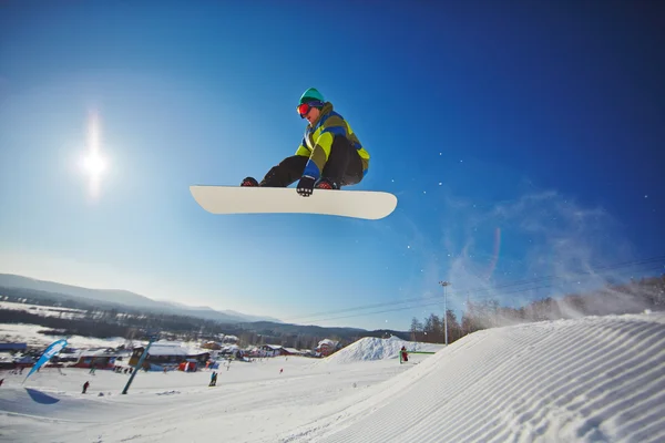 Sportlicher Mann auf Snowboard fliegt über Schneewehe — Stockfoto