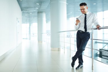 Koridorda cep telefonu bakarak işadamı