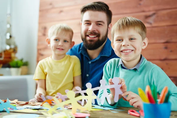 Crianças fazendo figuras de papel com o pai — Fotografia de Stock