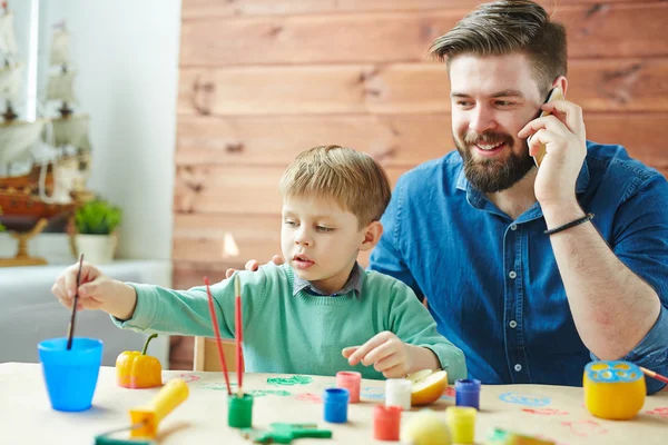 Jongen schilderen terwijl zijn vader praten aan de telefoon — Stockfoto