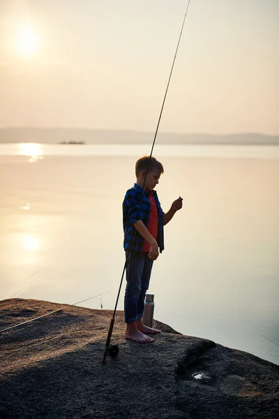 Милий хлопчик зі стрижнем на озері або річці — стокове фото
