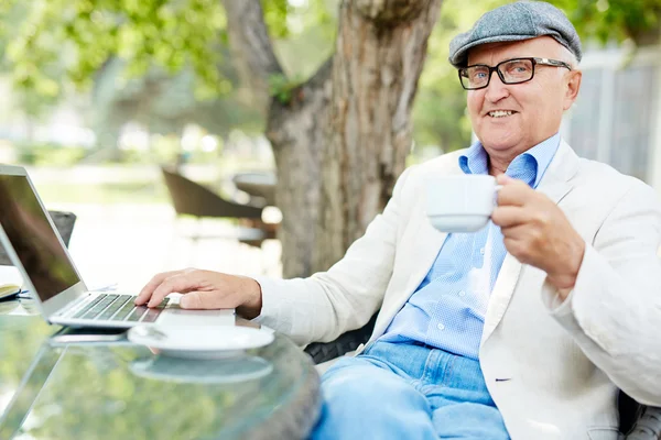 Starszy człowiek freelancing w kawiarni chodniku — Zdjęcie stockowe