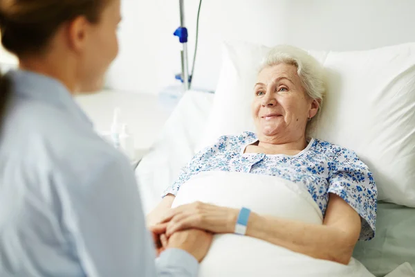 Mujer apoyando a su abuela en cama de hospital — Foto de Stock