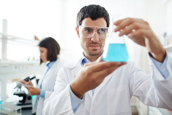 Ученый держит стекло с химической жидкостью — стоковое фото