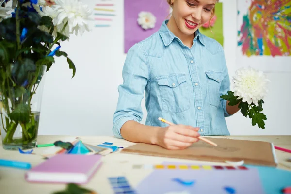 Mulher designer desenhando uma flor em seu bloco de notas — Fotografia de Stock