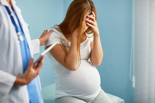Доктор поддерживает обеспокоенную беременную женщину — стоковое фото