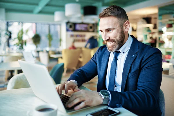 Zakenman werkt aan laptop in café — Stockfoto