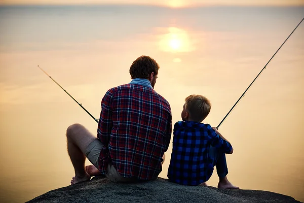 Far och son fiskar vid solnedgången — Stockfoto