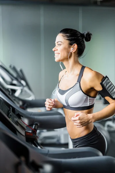 Sportig kvinna springer på löpband i gymmet — Stockfoto