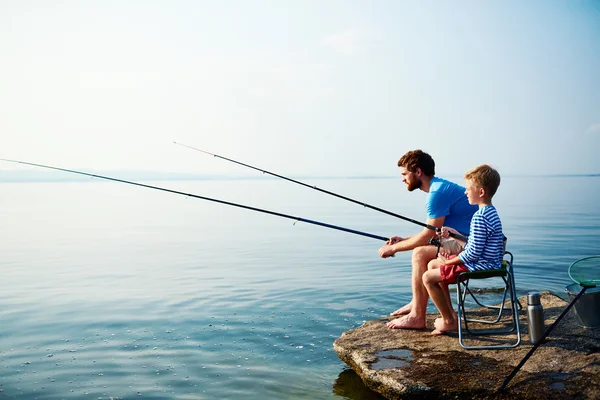 Young man and boy fishing together — Stock Photo, Image