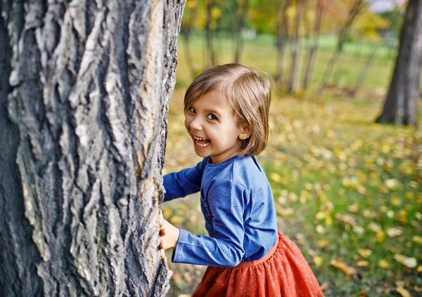 Meisje spelen verstoppertje in park — Stockfoto