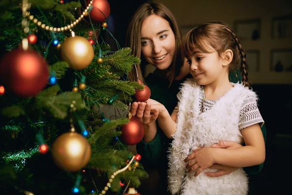 Девочка и ее мать возле рождественской елки — стоковое фото