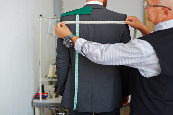 Tailor measuring back width of jacket 