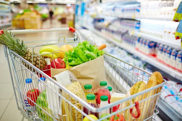 Verschillende soorten voedselproducten in winkelwagen — Stockfoto