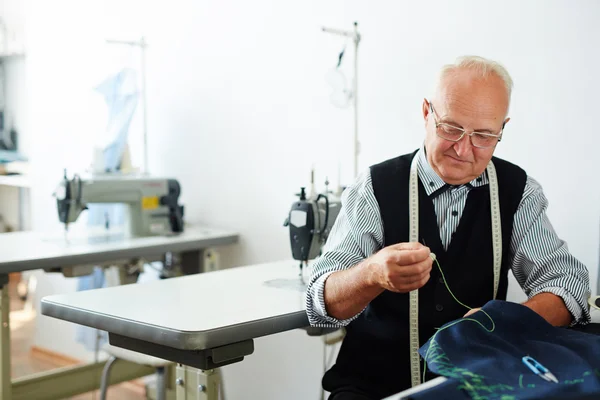 Человек шитье одежды в швейной мастерской — стоковое фото