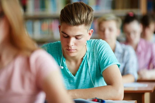 Estudiante realizando tarea escrita en la lección — Foto de Stock