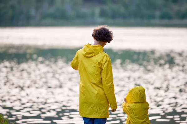 Mulher e seu filho em capas de chuva amarelas — Fotografia de Stock