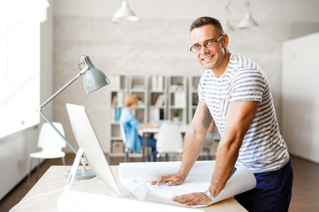 Young architect with sketch looking at camera 