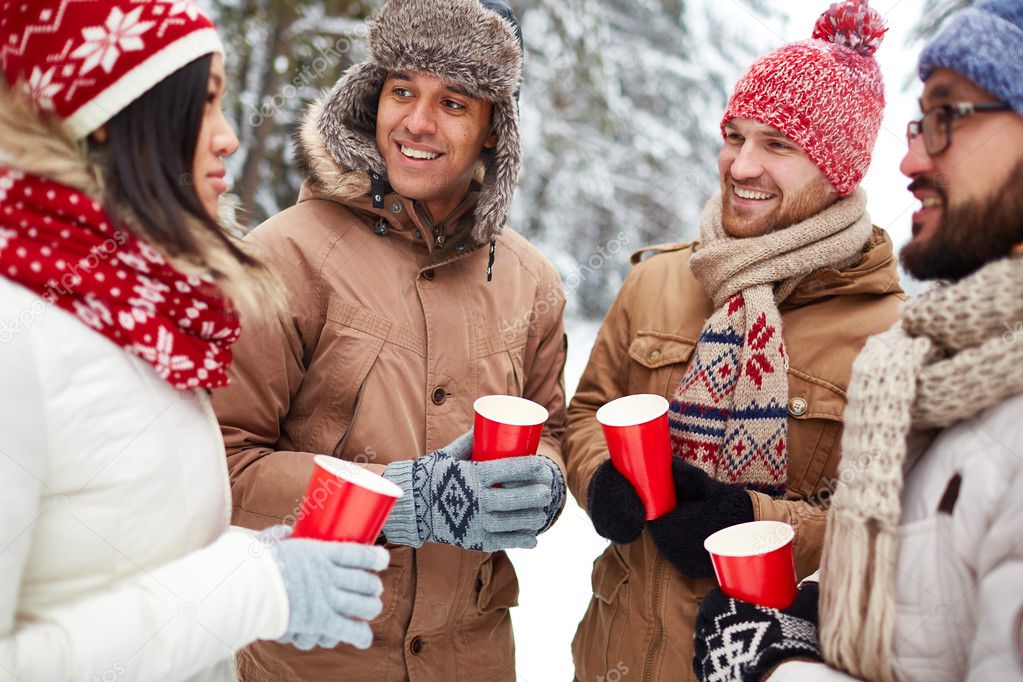 Happy people with drinks talking outdoors