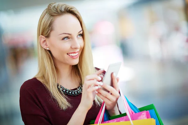Klant met behulp van mobiele telefoon in winkelcentrum — Stockfoto