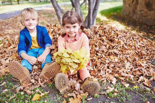 Słodkie dzieci siedzi na ziemi w parku — Zdjęcie stockowe