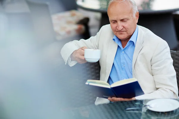 Senior-Geschäftsmann liest im Café — Stockfoto