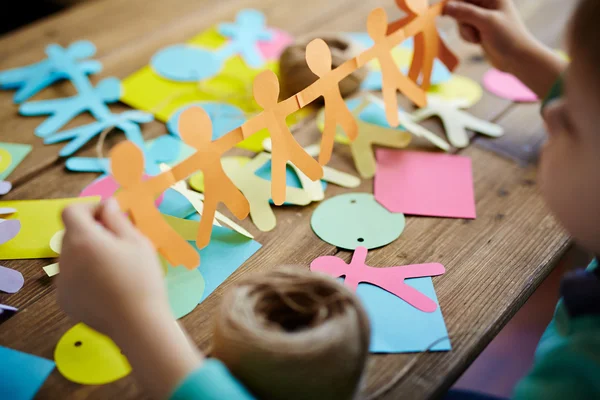 Little boy holding paper figures of people — Stock Photo, Image