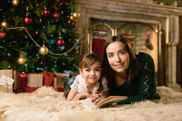 Happy woman and her daughter by Christmas tree — ストック写真