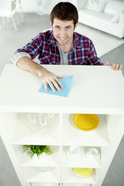 Man cleaning shelves in his house clipart