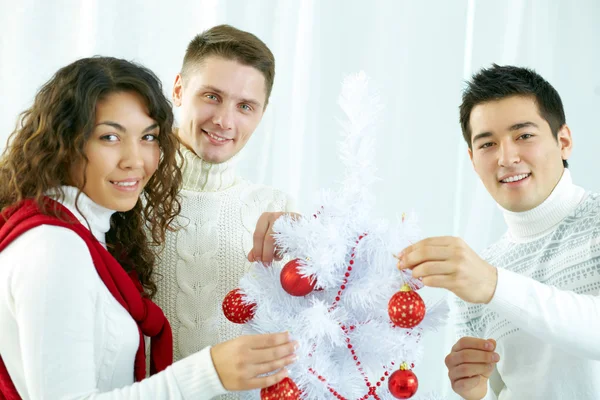 Friends decorating Christmas tree — Stock fotografie