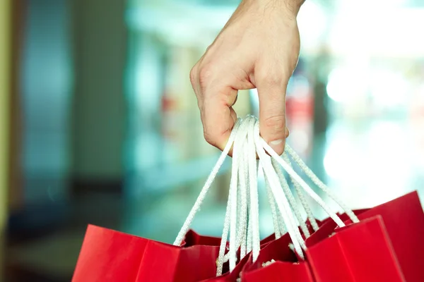 Mannenhand bedrijf shopping tassen — Stockfoto