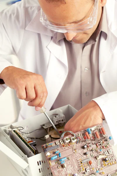 Engenheiro com chave de fenda examinando placa de circuito — Fotografia de Stock