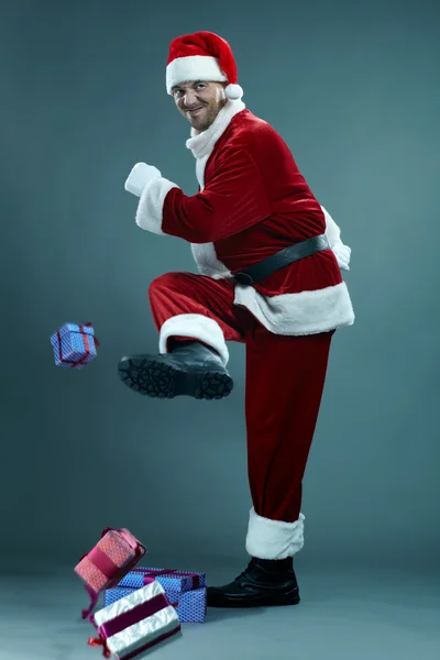 Santa Claus kicking gift boxes — Stock fotografie