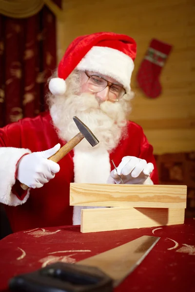 Babbo Natale che lavora con martello e legno — Foto Stock