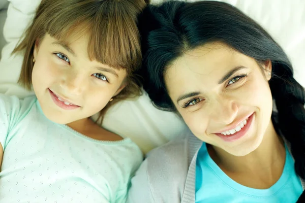 Sonriente madre y su hija acostadas en la cama —  Fotos de Stock