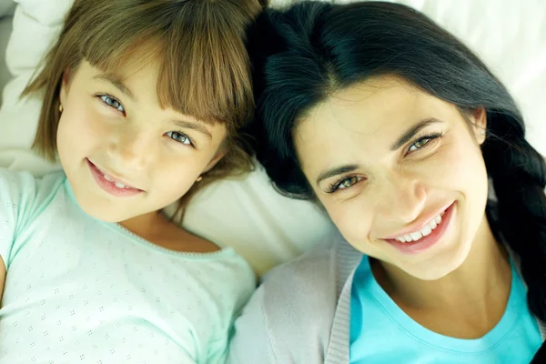 Smiling mother and her daughter lying in bed — Φωτογραφία Αρχείου