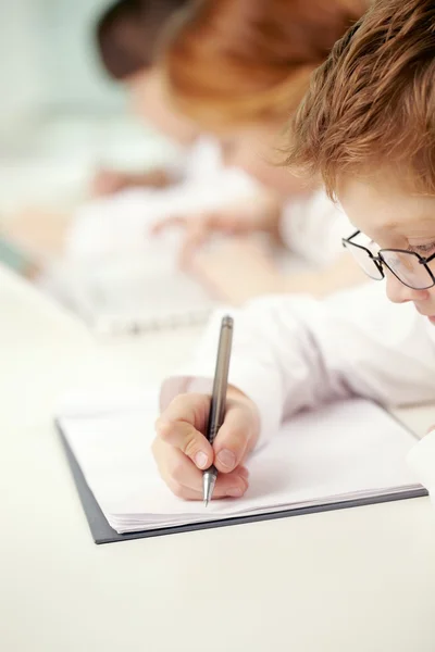 Petit garçon écrivant au bureau à l'école — Photo