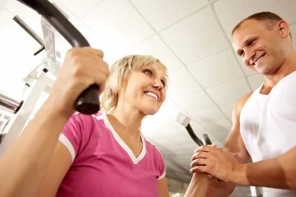 Trainer helpen van vrouw met oefeningen in de sportschool — Stockfoto